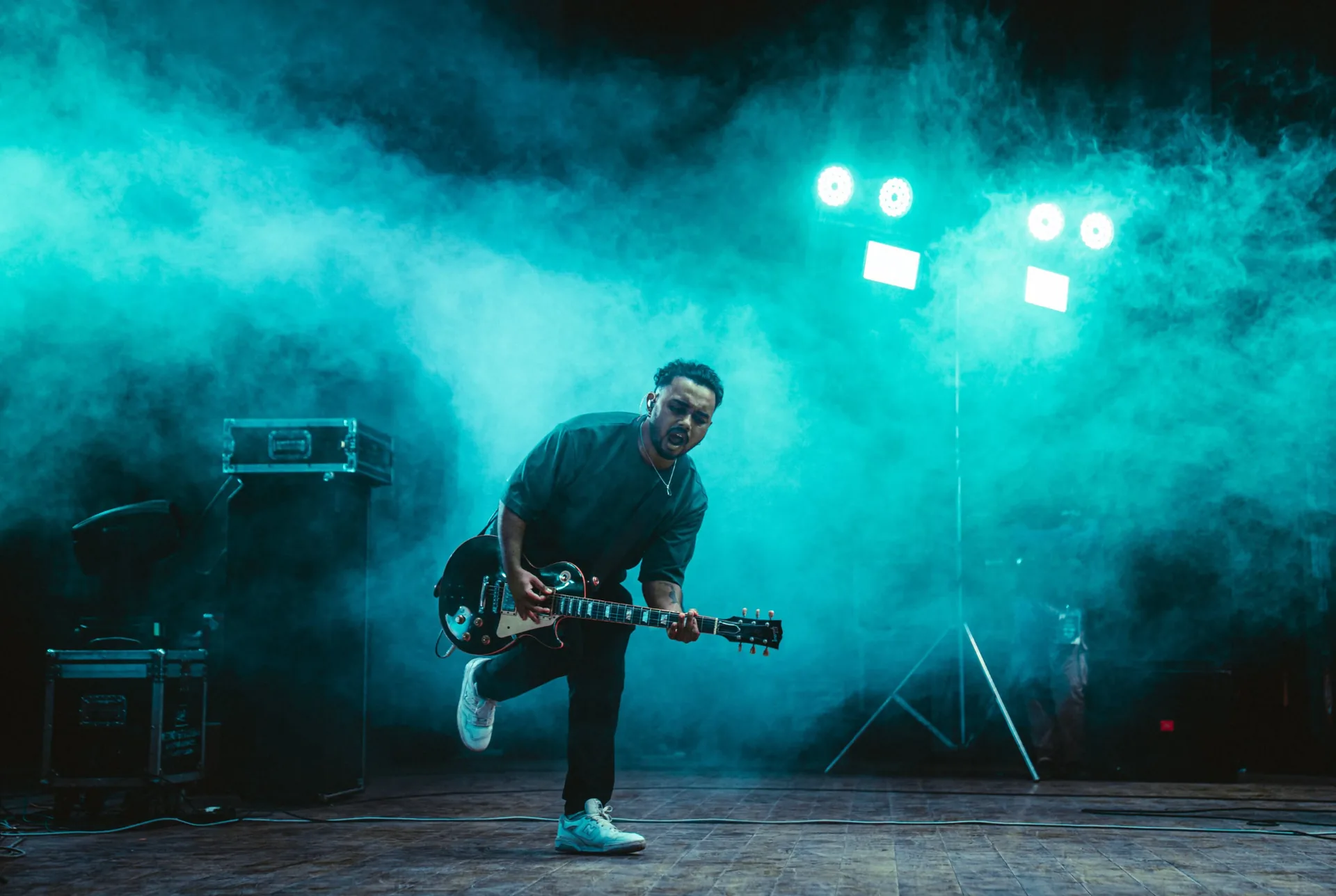 Ifaz playing electric guitar on a teal-lit stage